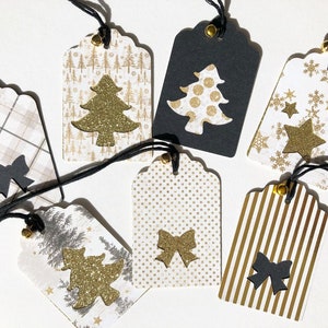 Pu&ograve; includere: Set di sette etichette regalo di Natale con vari design. Le etichette sono in carta e presentano accenti dorati e neri. Alcune etichette hanno un design a forma di albero di Natale, mentre altre hanno un design a forma di fiocco o di fiocco di neve.