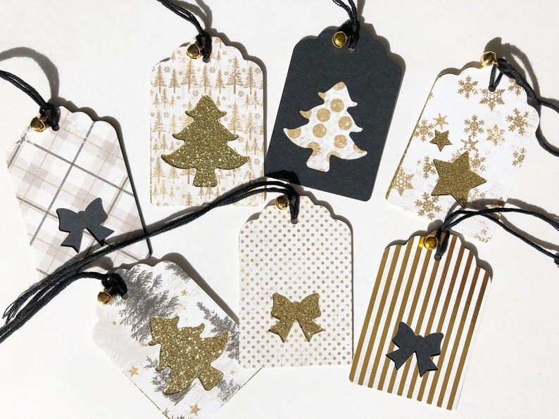 Pu&ograve; includere: Set di sette etichette regalo di Natale con vari design. Le etichette sono in carta e presentano accenti dorati e neri. Alcune etichette hanno un design a forma di albero di Natale, mentre altre hanno un design a forma di fiocco o di fiocco di neve.