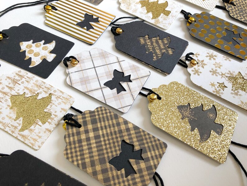 Pu&ograve; includere: Una collezione di etichette regalo di Natale con vari design che presentano glitter nero e oro, tartan e pois. Le etichette hanno un ritaglio di albero nero con uno sfondo di glitter oro e il testo "To & From" con un design di albero di Natale.