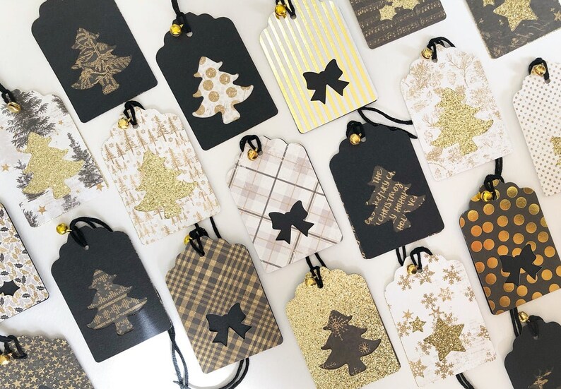 Pu&ograve; includere: Una collezione di 14 etichette regalo di Natale con vari design. Le etichette sono nere, dorate, bianche e marroni con diversi motivi, tra cui scozzese, pois, fiocchi di neve e glitter. Alcune etichette hanno una forma di albero di Natale ritagliata con un albero di glitter dorato all'interno. Alcune etichette hanno il testo "The very merry Christmas & Happy New Year!" stampato su di esse.