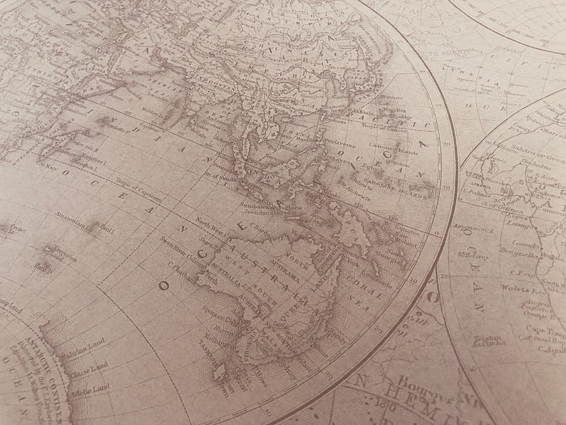 May include: A vintage world map printed on paper with a brown background. The map shows the continents of Asia, Australia, and Antarctica. The map is labeled with the names of countries and oceans.