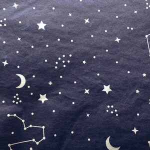 May include: A dark blue background with a white crescent moon and stars, including a constellation of stars.