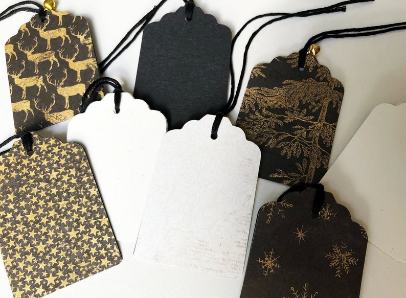 Pu&ograve; includere: Assortimento di etichette regalo nere e bianche con disegni in foglia d'oro. Le etichette presentano vari motivi, tra cui renne, stelle, fiocchi di neve e alberi. Ogni etichetta &egrave; dotata di uno spago nero.