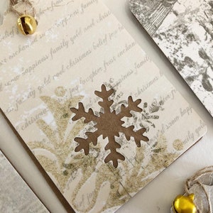 May include: A white gift tag with gold glitter and a brown snowflake cutout. The tag has a handwritten message that reads "ter fro't eachan oil suo Seppinos fame ted w sappiness family gold aoel christ faty gold roel christmas belief jou la christma jay foughter frost enchan Capines family christmas b ter fr d srow happ emily gola".