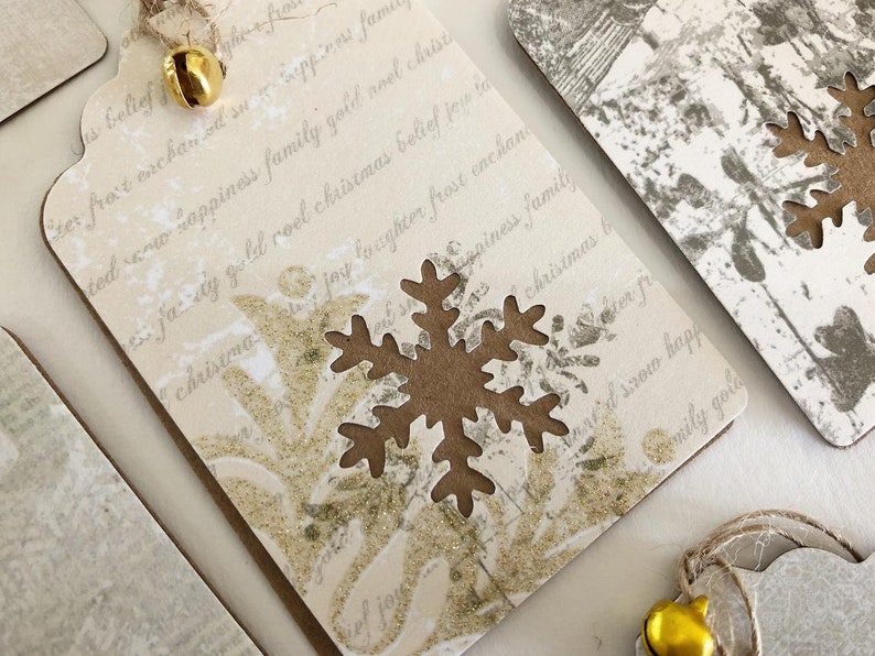 May include: A white gift tag with gold glitter and a brown snowflake cutout. The tag has a handwritten message that reads "ter fro't eachan oil suo Seppinos fame ted w sappiness family gold aoel christ faty gold roel christmas belief jou la christma jay foughter frost enchan Capines family christmas b ter fr d srow happ emily gola".