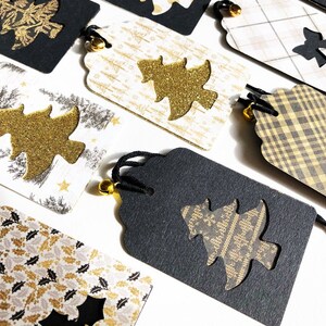 Pu&ograve; includere: Un set di otto etichette regalo di Natale con una variet&agrave; di motivi e design. Le etichette sono nere, bianche e dorate con una finitura scintillante. Ogni etichetta presenta un design ritagliato di un albero di Natale o di un fiocco. Le etichette sono legate con uno spago nero e hanno una piccola campana.