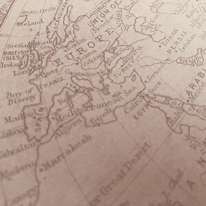 May include: A vintage world map with a focus on Europe, the Mediterranean Sea, and the Middle East. The map is printed in brown ink on a cream-colored background.