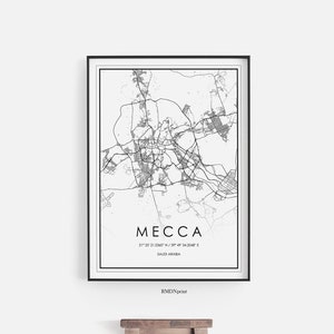 Pode incluir: Uma impressão de mapa em preto e branco de Meca, Arábia Saudita, em uma moldura preta. O mapa é intitulado "Mecca" e inclui as coordenadas 21°25'02.2"N 39°49'36.7"E. A impressão está pendurada em uma parede branca acima de um banquinho de madeira.