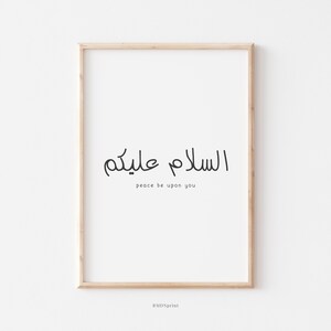 May include: A framed print with the Arabic phrase "السلام عليكم" which translates to "Peace be upon you" in English. The print is on a white background with a light wood frame.
