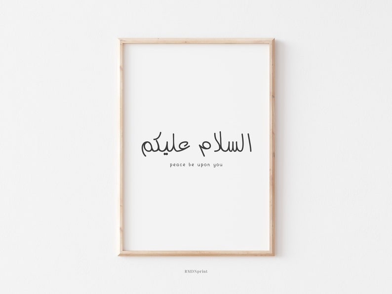 May include: A framed print with the Arabic phrase "السلام عليكم" which translates to "Peace be upon you" in English. The print is on a white background with a light wood frame.
