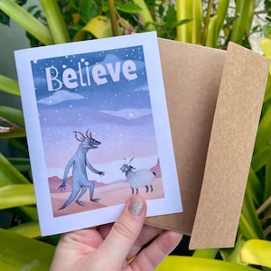 Chupacabra in de woestijn met een geit "Believe"-wenskaart, Chupacabra-aanmoedigingskaart voor vriend, grappige chupacabra-cryptidekaart