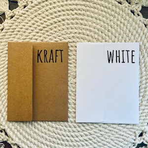 Two envelopes sitting on a table, one is white and one is brown to show the different envelope color options