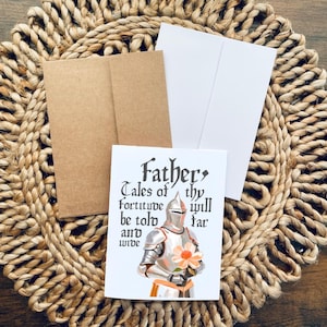 May include: A white card featuring a knight in silver armour holding a pink flower. The card reads "Father, Tales of thy fortitude will be told far and wide."