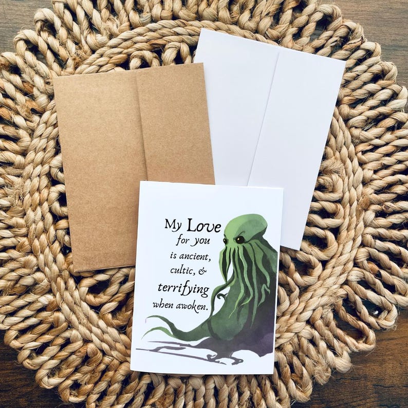 May include: Greeting card with a green tentacled creature illustration and the text "My Love for you is ancient, cultic, & terrifying when awoken." Includes a brown envelope and a white card.