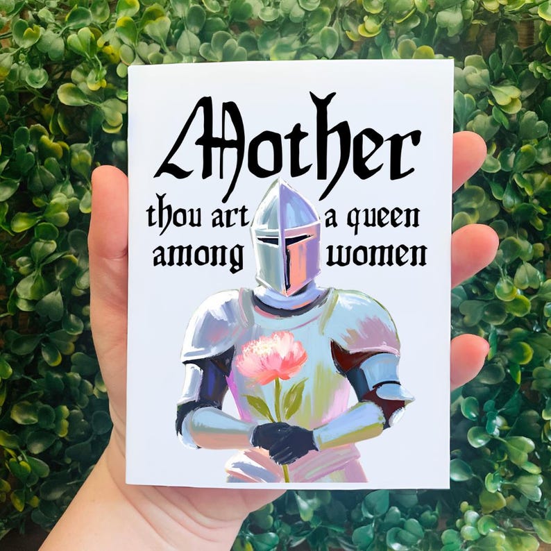May include: A white card with a knight in silver armor holding a pink flower. The card has black text that reads "Mother thou art a queen among women."