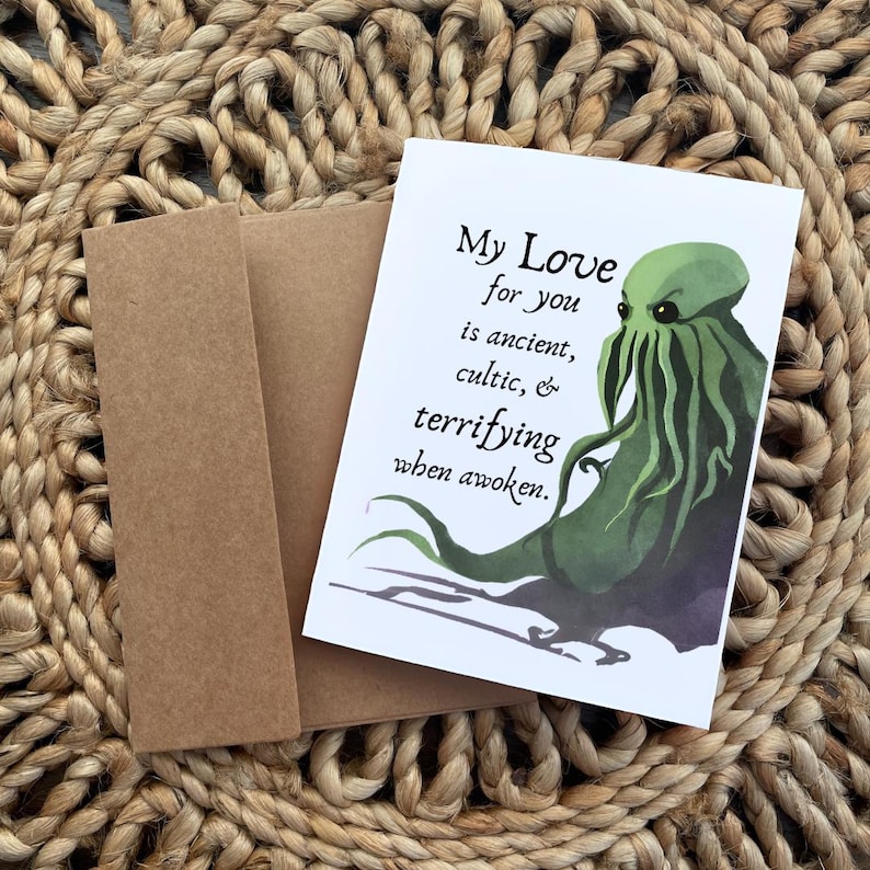 May include: Greeting card with a brown envelope. The card features the text "My Love for you is ancient, cultic, & terrifying when awoken." and a green illustration of a tentacled creature.