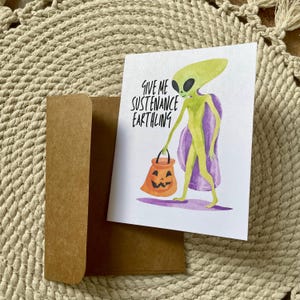 Une astuce extraterrestre amusante ou une carte d'Halloween - Donnez-moi de la nourriture pour un terrien. Carte d'Halloween extraterrestre, astuce amusante ou carte d'Halloween à traiter