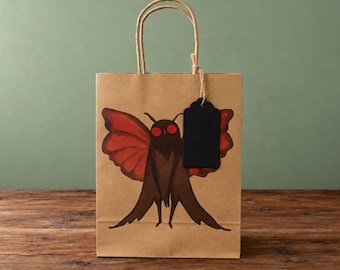 Bolsa de regalo rústica de papel kraft con etiqueta y diseño de la criatura críptida Mothman.