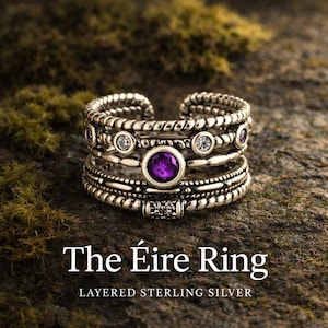Puede incluir: Anillo de plata de ley en capas con un diseño texturizado. El anillo presenta una gema púrpura grande y redonda y gemas claras más pequeñas. El texto "The Éire Ring" se muestra debajo del anillo.