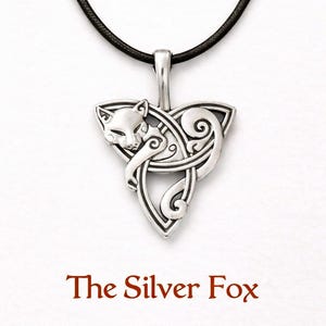 Puede incluir: Colgante plateado con un diseño de zorro en un nudo celta, suspendido de un cordón negro. El colgante presenta una cabeza de zorro y patrones arremolinados. El texto "The Silver Fox" se muestra debajo.