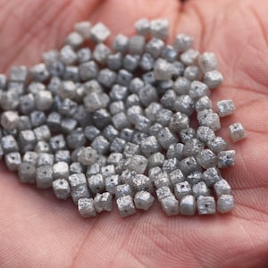 May include: A pile of small, gray, square-shaped diamonds.