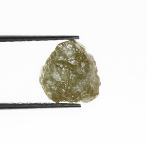 Peut inclure: Un diamant brut, vert et non poli, tenu dans des pinces. Le diamant est une pierre précieuse naturelle et brute.