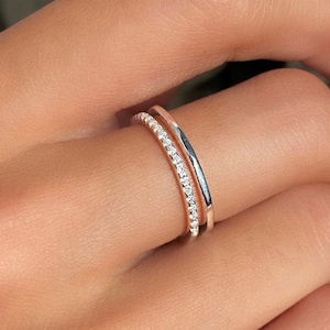 May include: A silver ring with a row of small clear stones on the top band and a plain band underneath.