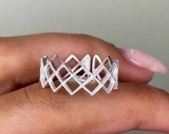 May include: A silver ring with a geometric design. The ring is made of multiple bands that are connected to form a lattice pattern.