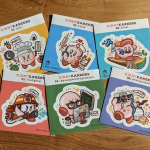Könnte beinhalten: Eine Sammlung von sechs farbenfrohen Aufklebern mit Kirby-Charakteren in verschiedenen Berufen. Jeder Aufkleber hat ein einzigartiges Design, darunter ein Koch, eine Krankenschwester, ein Künstler, ein Feuerwehrmann, ein Entwickler/Programmierer und ein Fotograf. Auf einer Holzoberfläche.