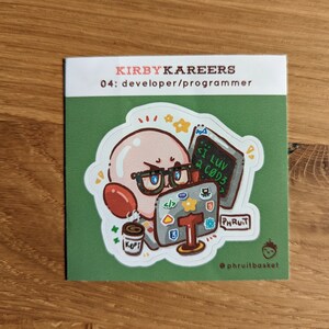 May include: A square sticker featuring a cartoon character with glasses, a red balloon, and a coffee cup. The sticker has the text "KIRBYKAREERS 04: developer/programmer" and a computer with the text "I LUV 2 CØD3". The sticker is on a green background.