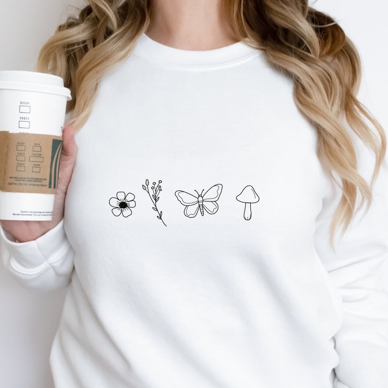 May include: White sweatshirt with a black line drawing of a flower, a stem with leaves, a butterfly, and a mushroom.