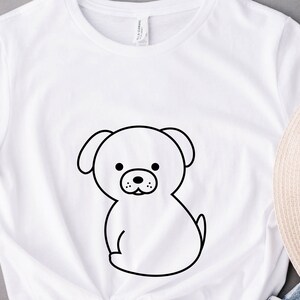 May include: White t-shirt with a black line drawing of a cartoon dog on the front.