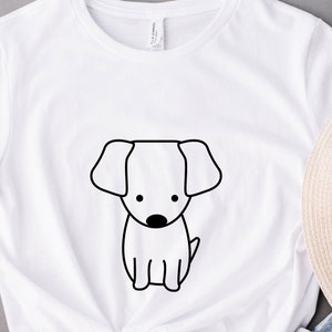 May include: White t-shirt with a black line drawing of a dog on the front.