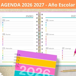 Puede incluir: Agenda abierta con el texto "AGENDA 2026 2027 - Año Escolar". La agenda está abierta a enero de 2027, con un lápiz de colores y una agenda cerrada con el año 2026. La agenda tiene encuadernación en espiral.