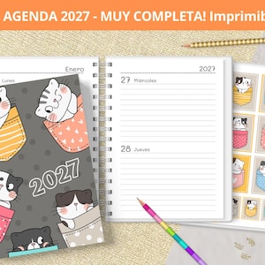 May include: A 2027 spiral-bound planner featuring a dark gray cover with cartoon cats in pockets. The interior pages show lined daily entries for January 25, 27, and 28. A separate sheet displays a grid of cat stickers. A rainbow pencil is included.