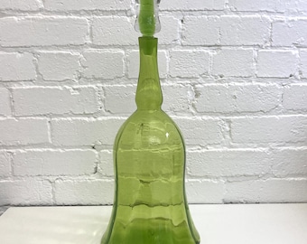 May include: A large, green glass decanter with a bell-shaped body and a clear glass stopper.