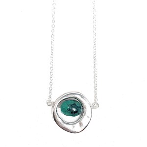 May include: A silver necklace with a circular pendant featuring a green gemstone. The pendant is made of two overlapping circles, with the gemstone nestled in the center.