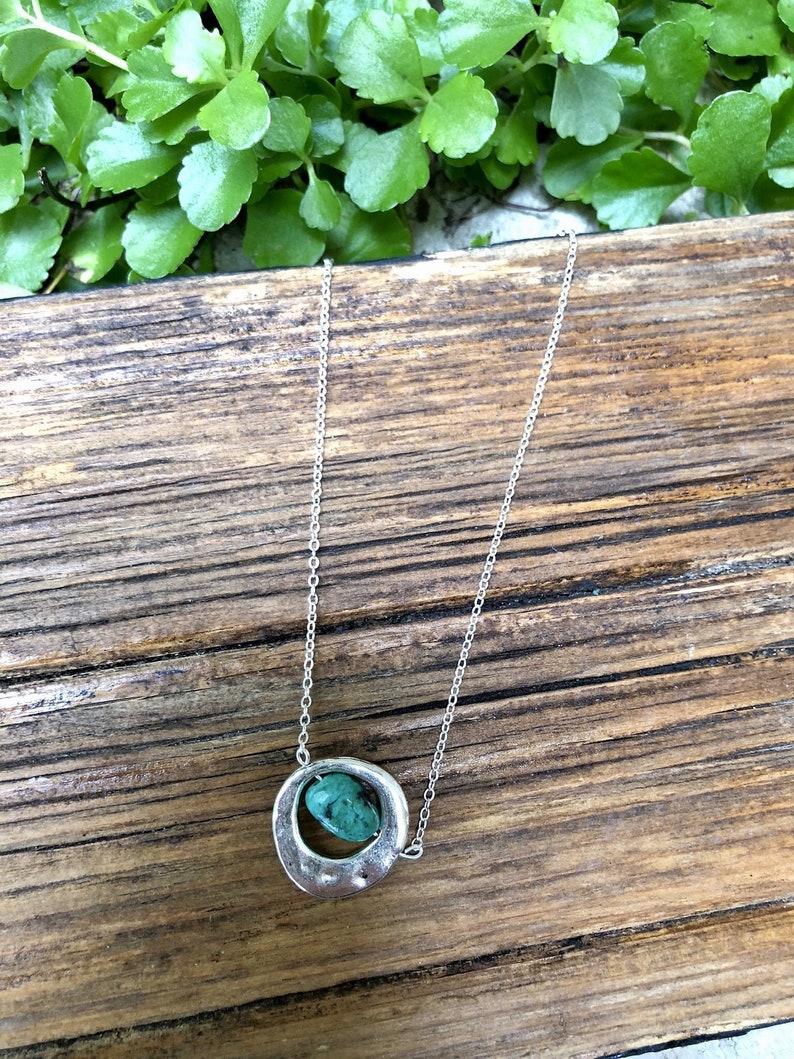 May include: A silver chain necklace with a silver pendant featuring a turquoise stone.
