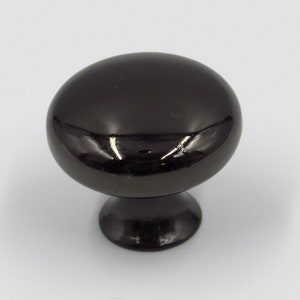 May include: A black cabinet knob with a round, slightly domed top and a smaller, round base.