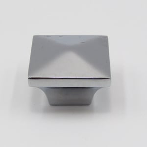 May include: A square-shaped, silver-toned cabinet knob with a pyramid-shaped top.