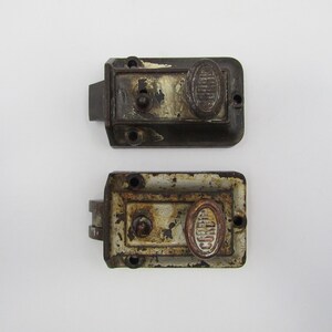 May include: Two antique door latches with a white and brown finish. The latches have a round knob with the word "CORBIN" embossed on them.