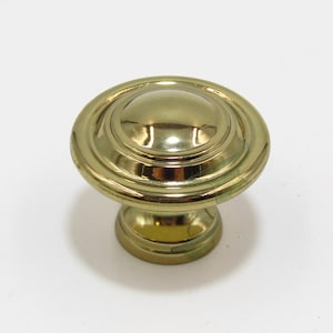 May include: A gold-toned cabinet knob with a round, domed top and a fluted base.