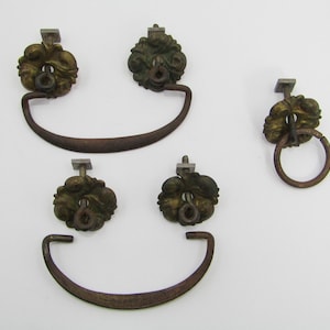 May include: Set of four antique brass drawer pulls with ornate floral designs. Two pulls have a ring handle, and two have a curved handle.