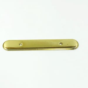 May include: A polished brass-colored metal plate with rounded ends and two small holes. The plate has a smooth, reflective surface and is likely a decorative or functional hardware component.