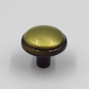 May include: A single cabinet knob with a rounded, brass-colored top and a dark brown stem. The knob has a slightly aged appearance, suggesting a vintage or antique style. The hardware is designed for use on drawers or cabinet doors.