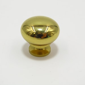 Op de afbeelding: Een ronde, gepolijste gouden kastknop met een glad, glanzend oppervlak.