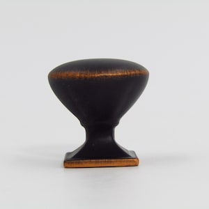 May include: A black and copper cabinet knob with a rounded top and a square base.