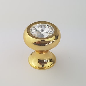 May include: Gold cabinet knob with a clear crystal top.
