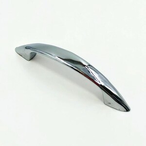 May include: A polished chrome cabinet handle with a smooth, arched design. The hardware features a reflective, metallic silver finish and tapers at both ends, providing a sleek, curved silhouette for attachment to furniture or cabinetry doors.