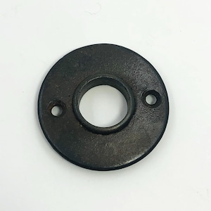 以下が含まれることがあります： 中央の穴と2つの小さな穴がある、円形の濃い茶色の金属フランジ。 フランジはテクスチャ加工された表面を持ち、鋳鉄または同様の材料で作られているようです。 デザインはシンプルで機能的です。